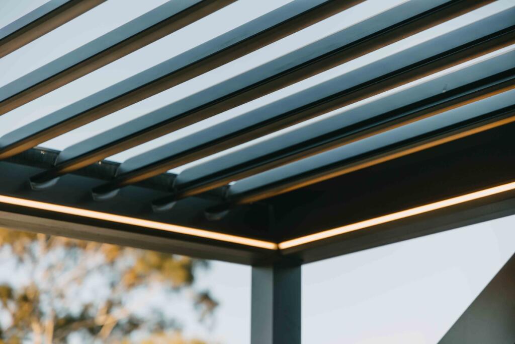 Close-up of automated louvre roof system with integrated LED lighting at sunset