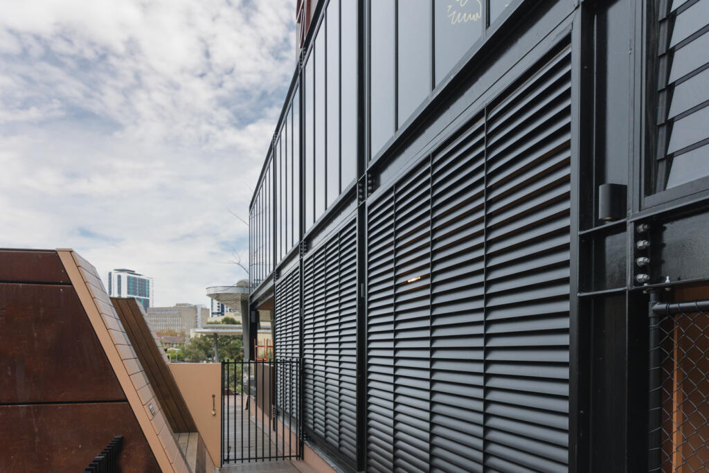 Black aluminium louvre screens installed on upper-level windows of modern commercial building