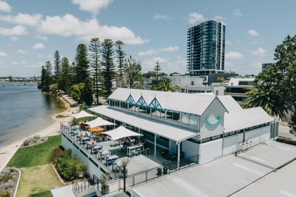 Beachfront hospitality venue with white retractable roof and outdoor dining overlooking the river