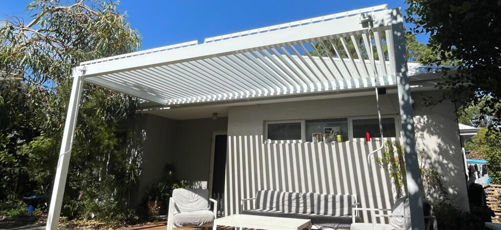 White louvre roof pergola over patio with outdoor seating, attached to single-storey home