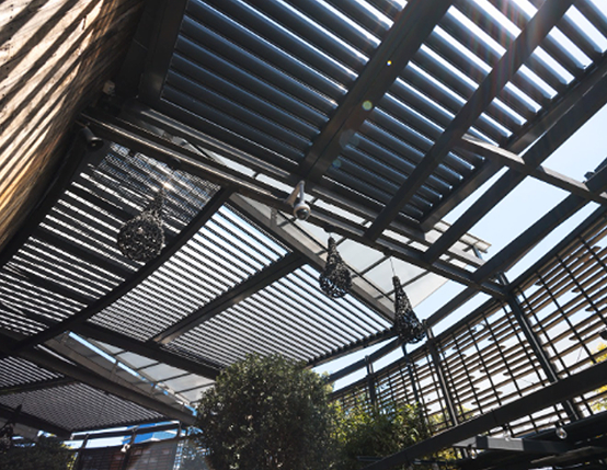 Black louvre roof system with integrated lighting above commercial outdoor dining area