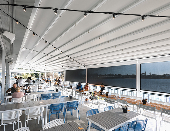 Retractable roof and outdoor blinds covering waterfront dining area at a commercial venue